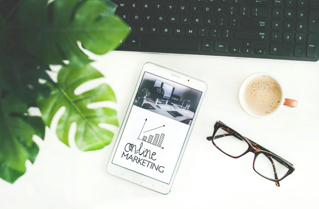 Flat-lay of an ipad, showing an Online Marketing graphic, pair of glasses and a cup of coffee